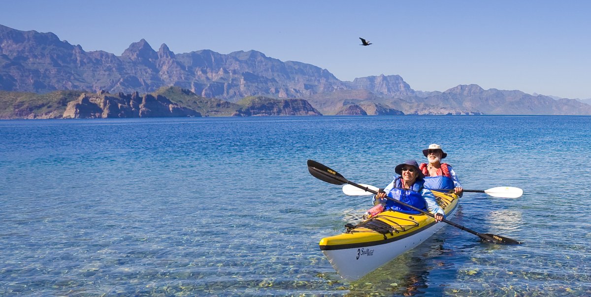 Couple in a tandem kayak paddling away from various islands in Loreto Bay, Baja California Sur