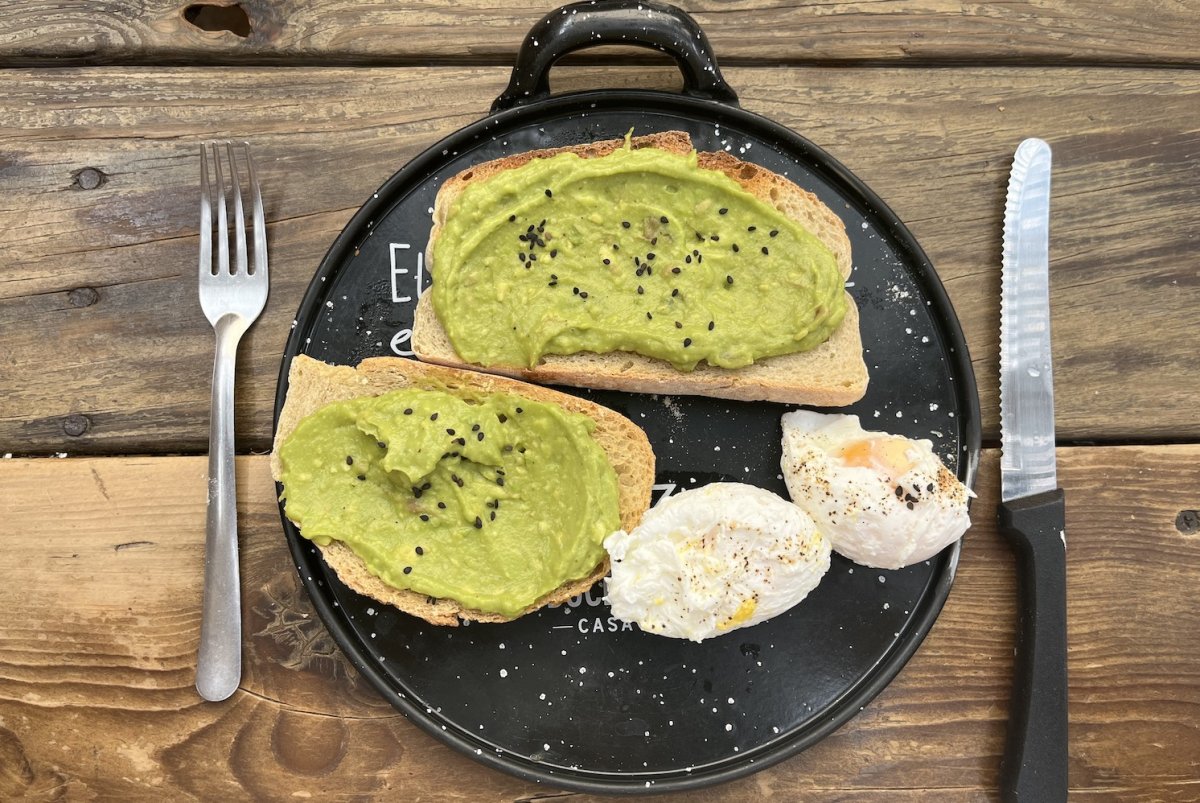 A plate of Avocado toast with two poached on a black and white speckled pate 
