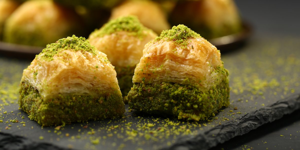 Three pistachio Turkish baklava pastries on a serving plate