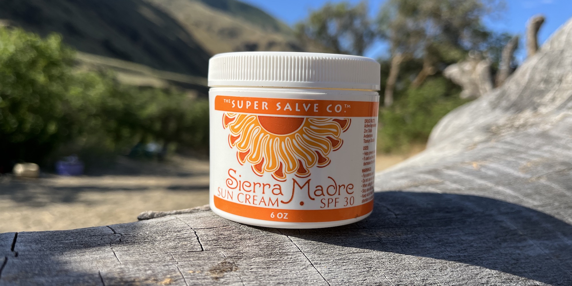 Sierra Madre super salve sunscreen resting on a log on a sunny day