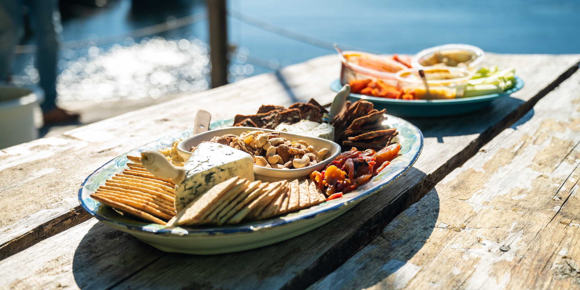 A plate of cheese and crackers on a wooden deck along the coast in British Columbia