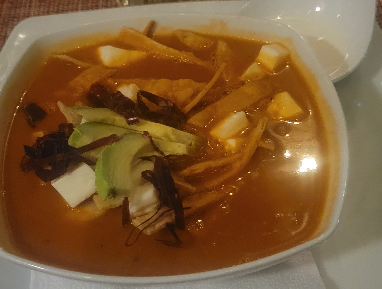 Tortilla soup in a white bowl