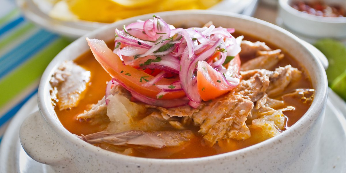 Ecuadorian Encebollado fish stew topped with pickled onions and tomatoes