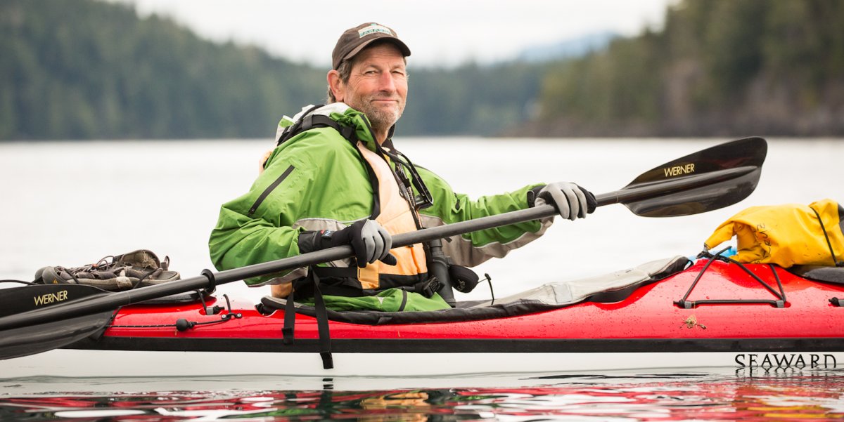 Kayaker smiling while paddling in a red single Seward kayak in British Columbia