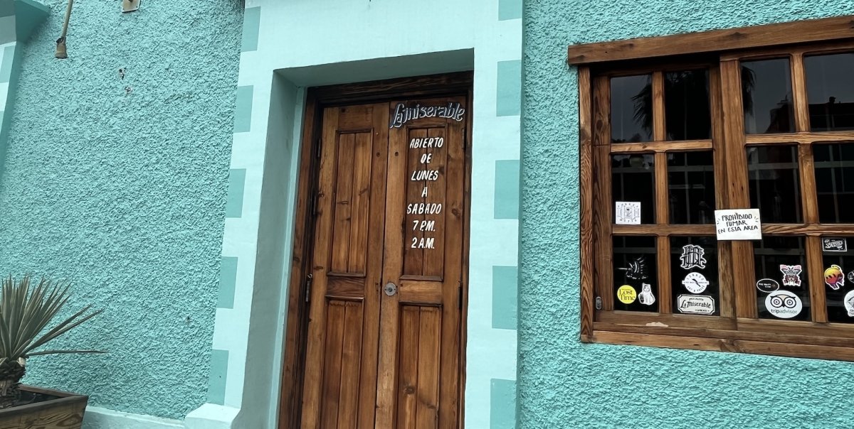 A blue building with a wooden door that enters to a mezcal bar in La Paz, Baja California Sur