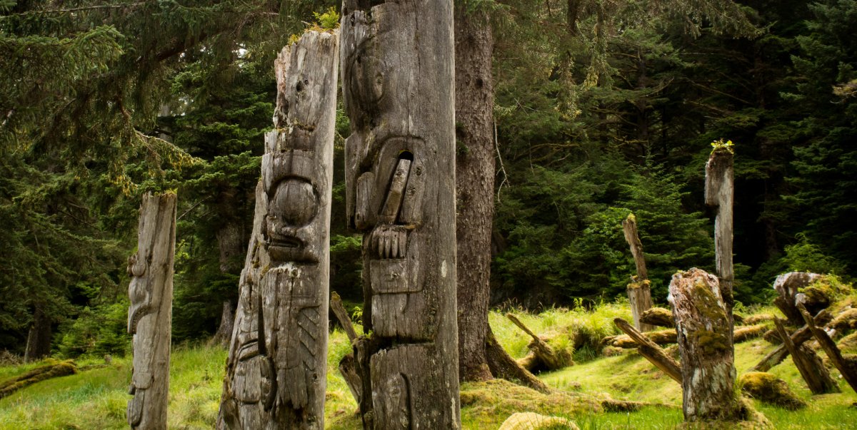 Series of indigenous totem poles in a lush green forest in British Columbia near Vancouver Island