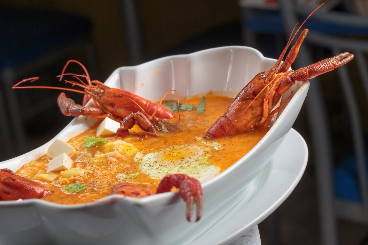 Seafood soup in a white bowl with red lobster