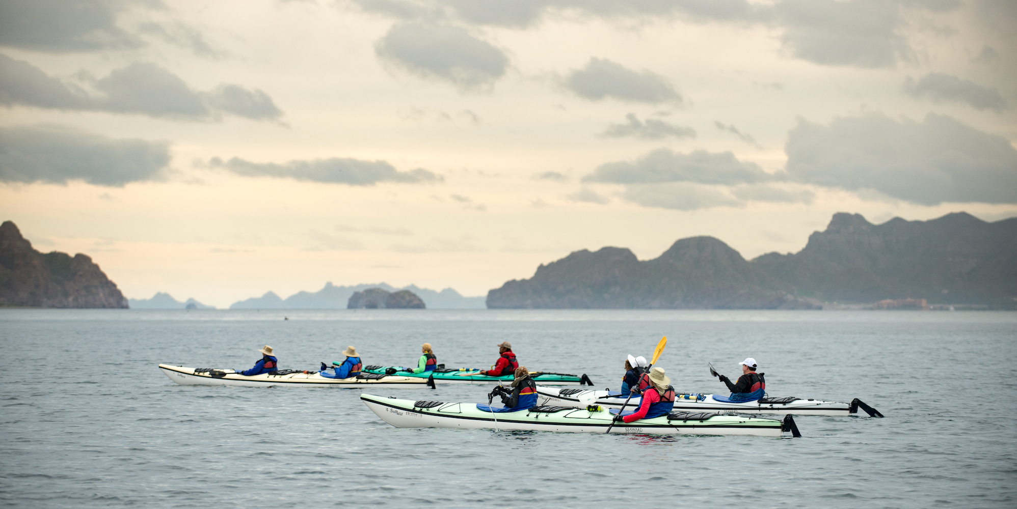 A group of sea kayakers looking at dark clouds rolling in 