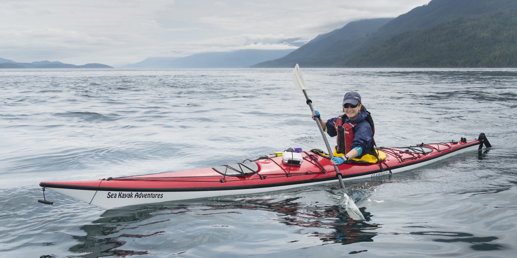 Sea kayaker paddling coastal waters near Port McNeill on northern Vancouver Island, British Columbia