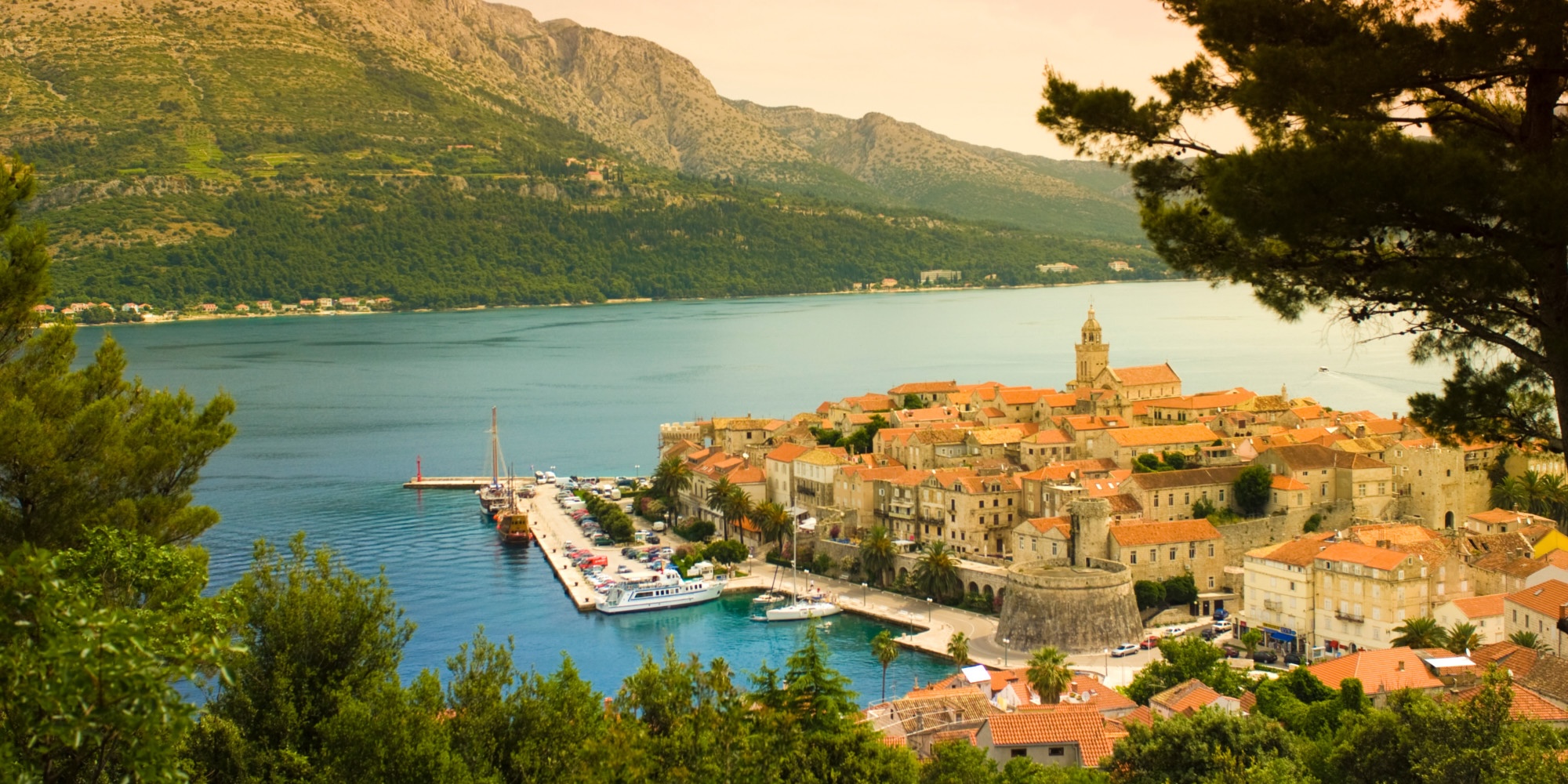 Panoramic view of a historic Croatian coastal town with terracotta rooftops overlooking the Adriatic Sea.