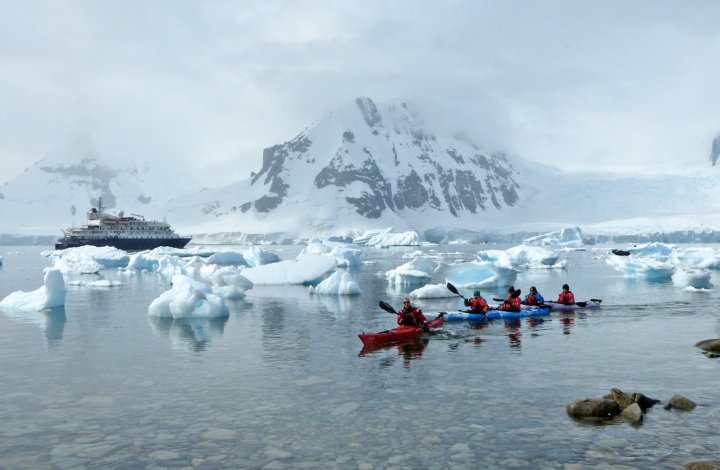 sea kayakers and cruise ship among ice in Antarctica
