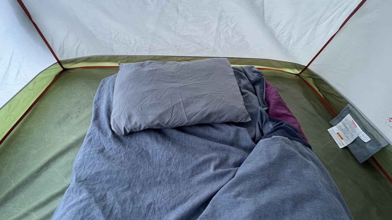 Sleeping bag with liner pulled open with a pillow inside of a tent