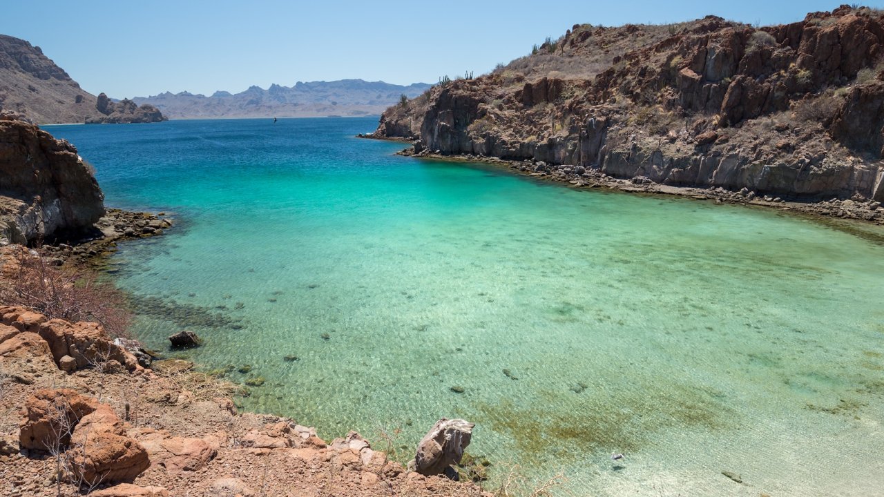 A bay in Loreto National Park with clear blue water and desert hills surrounding it. 