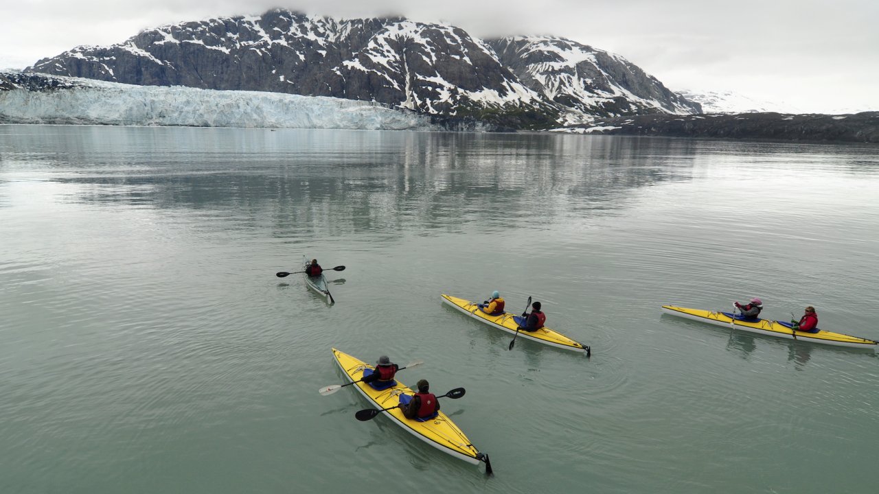 A group of yellow tandem sea kayaks in Alaska among glaciers on a cloudy day