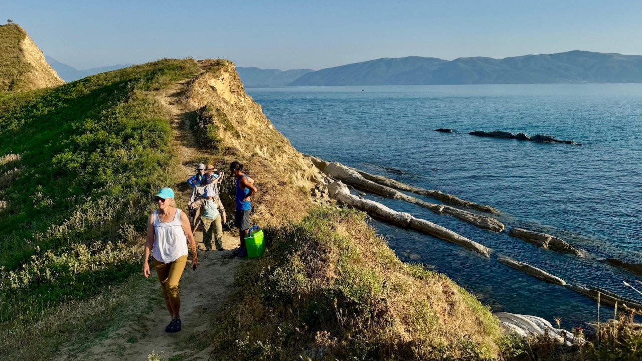 Hikers along a scenic coastal trail above the Adriatic Sea in Albania.