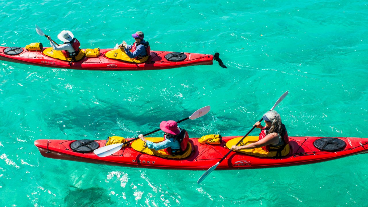 Two red tandem sea kayaks atop crystal clear blue water in Cuba