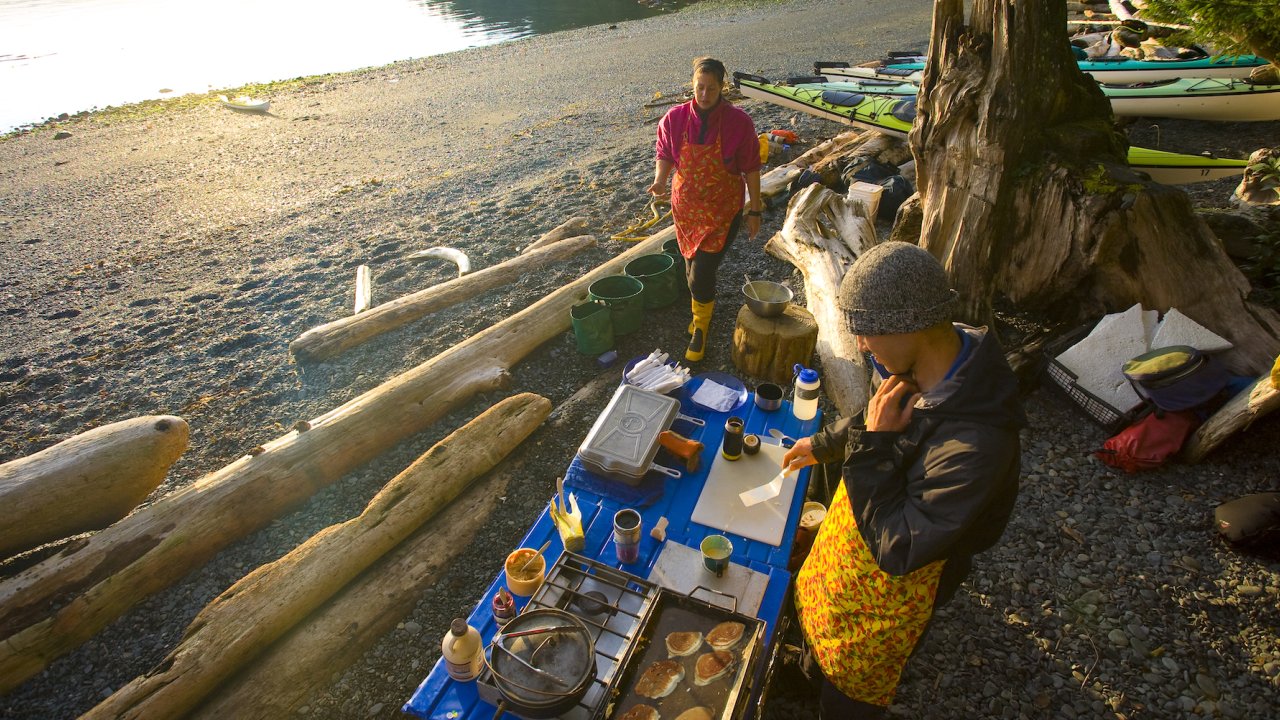 Guides making dinner while camping on a rocky beach in British Columbia