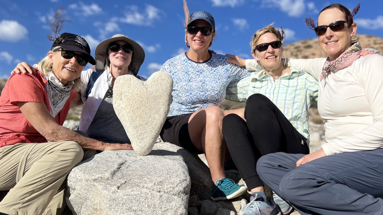 Group of guests smiling next to a heart rock found in Baja California Sur