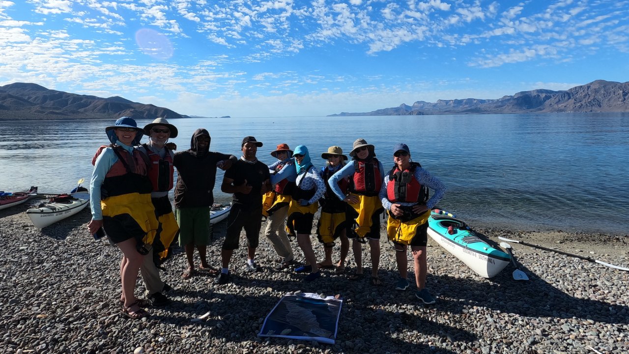 Group of kayakers smiling in front of the Sea of Cortez before a day of paddling