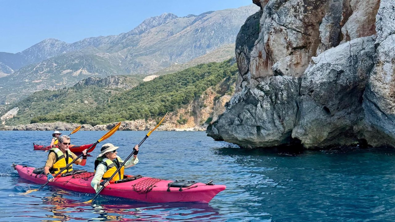 Two people in a tandem sea kayak paddling blue waters in Europe