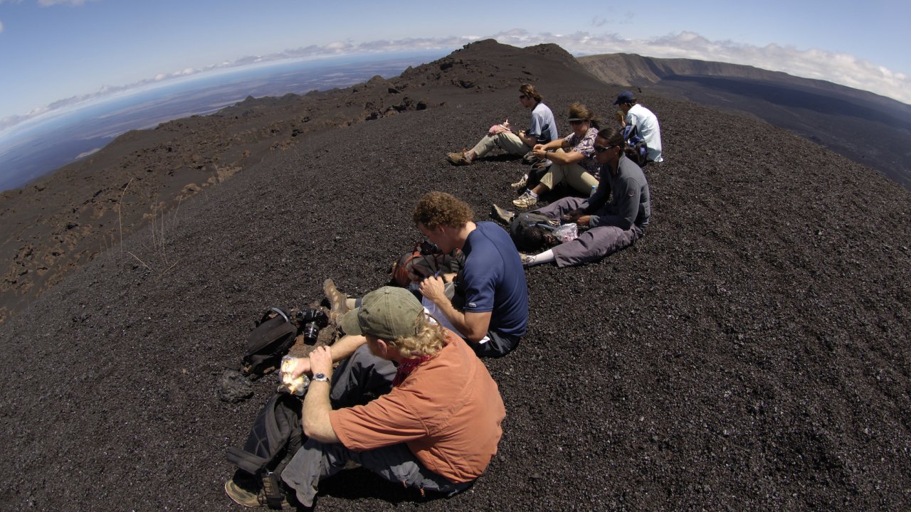 A group of people in the Galapagos Islands sitting on top of volcanic rock