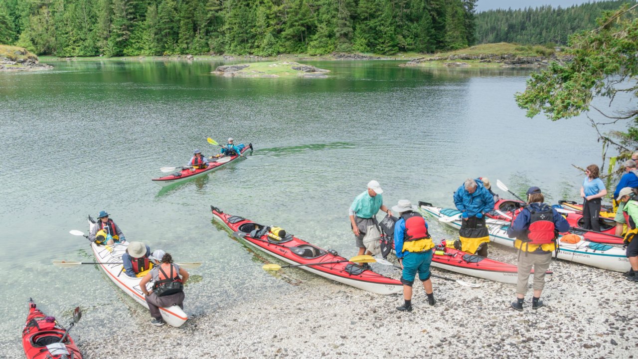 sea kayaks and people on wilderness beach in British Columbia