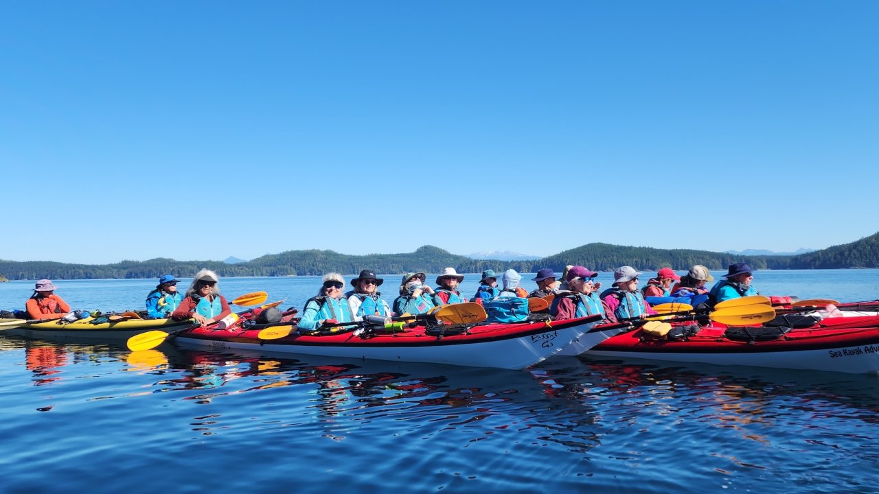 A group of kayakers paddling together in the Broughton Archipelago, British Columbia, enjoying a guided sea kayaking tour in Canada’s stunning coastal wilderness.