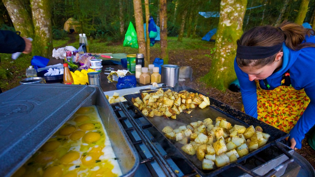 eggs and potatoes cooking on a camp griddle