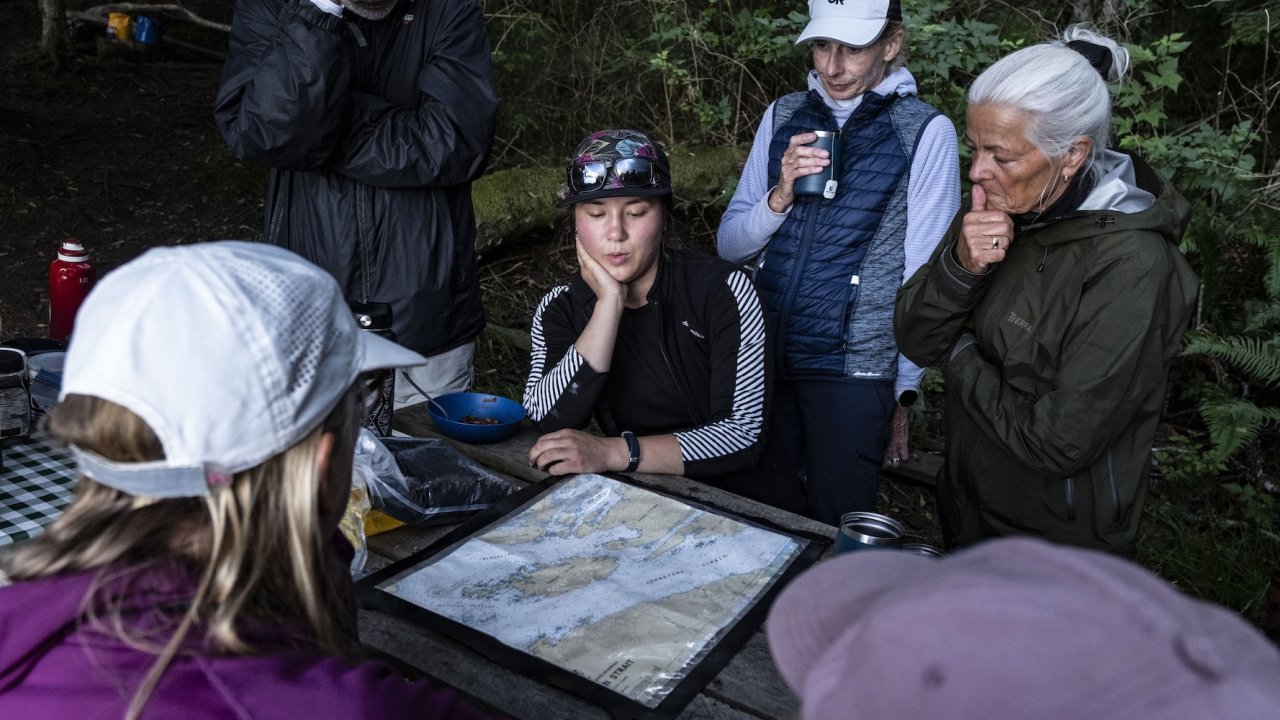 Sea kayaking guests gathered around a map during a guided orca kayaking tour in Johnstone Strait