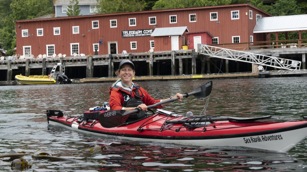 Kayakers paddling calm waters on a Johnstone Strait day kayaking tour in Canada with forested islands in the background.