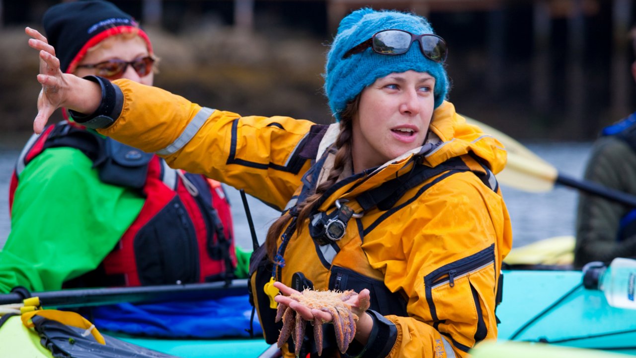female kayak guide holding sea start while pointing