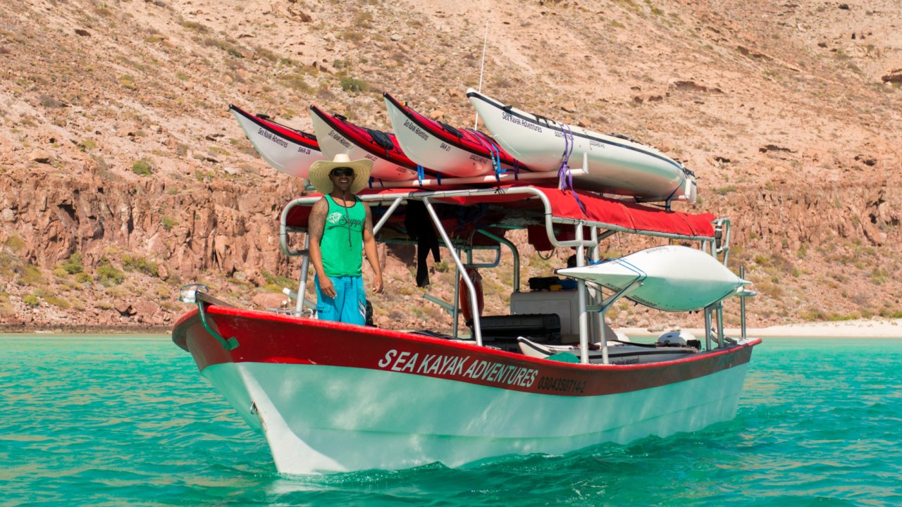 sea kayaks on rack on top of small boat