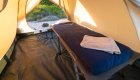 A cot, sleeping pad, and sheets inside of a canvas tent on the Galapagos Islands 