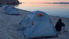 A person sitting next to their tent while watching the sunrise in Loreto Bay, Baja