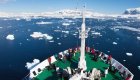 Birds eye view of the bow of a small cruise ship atop Antarctic waters filled with icebergs on a sunny day