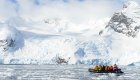 A group of people on a black raft in the water among glaciers in Antarctica