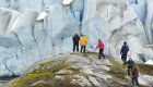 Group of people in different colored rain jackets hiking up a large boulder to see a view of glaciers in Alaska