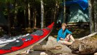 red kayak resting on logs