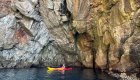 A sea kayaker in Europe exploring a rocky cliffside.