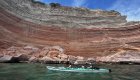 Tandem sea kayakers off the coast of La Paz paddling by a beautiful sandstone scape wall