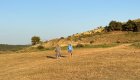 Two hikers in Albania walking through a field of tall yellow grass