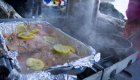 Fresh salmon with lemon and herbs cooking at a remote campsite by the ocean, part of a Canada camping tour paired with sea kayaking adventures in British Columbia.