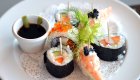 Sushi on a white plat atop a nicely set table with a white table cloth on a small cruise ship 
