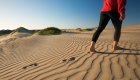 woman walking across sand dune