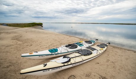 Two sea kayaks pulled up on shore on a beach along the Pacific Ocean