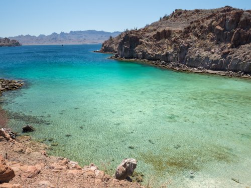 A bay in Loreto National Park with clear blue water and desert hills surrounding it. 
