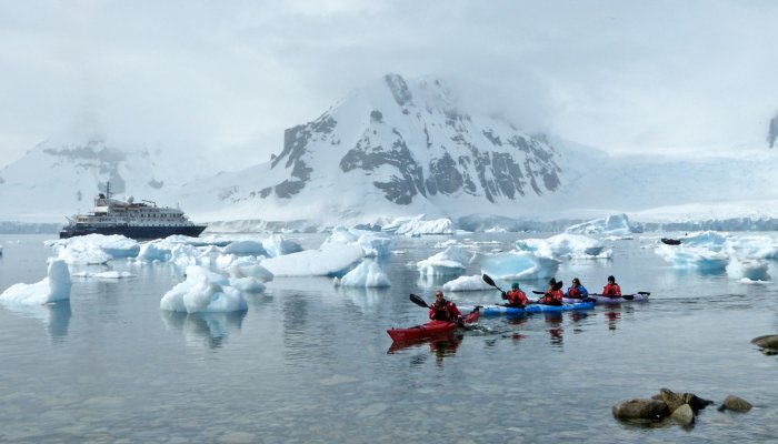 sea kayakers and cruise ship among ice in Antarctica
